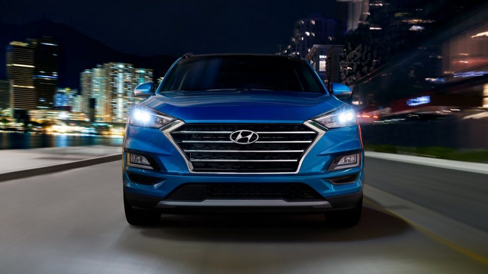 Front grille of a blue 2020 Tuscon driving through a city at night