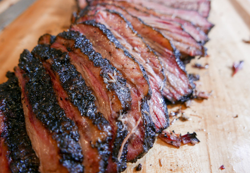 Sliced smoked brisket on a wooden cutting board.