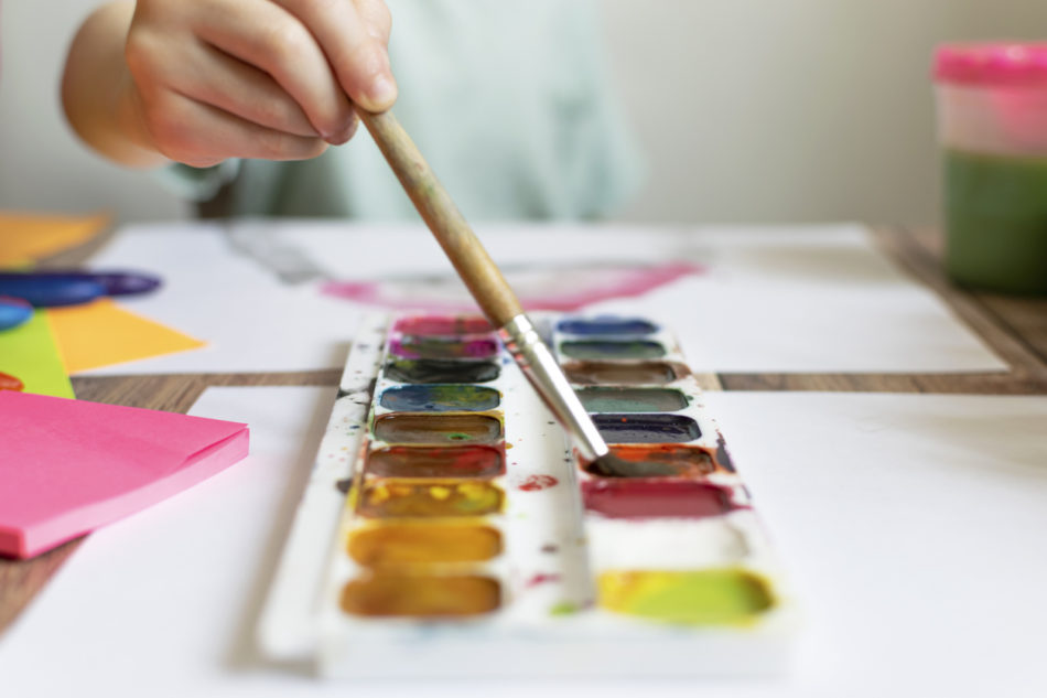 Child painting with a brush and watercolor paint