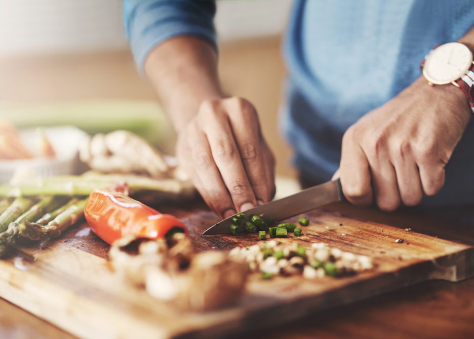 Cropped shot of a person preparing a meal at home, chopping vegetables.