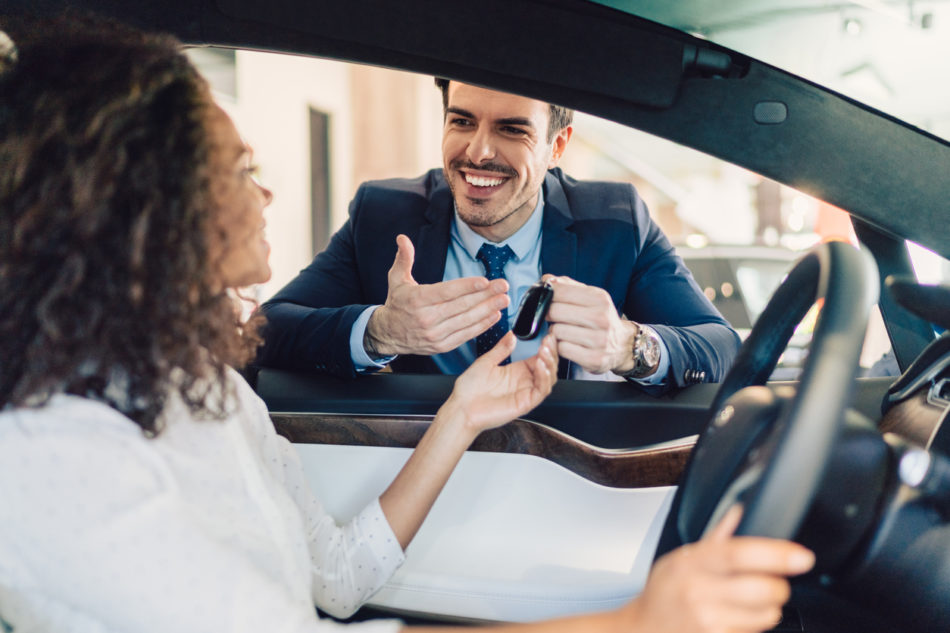 Smiling woman in the showroom enjoying luxury car