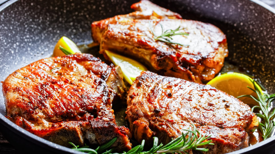 roasted pork chops with rosemary sprigs and lemon slices