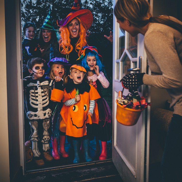 Group of children and their parents playing trick or treat on Halloween.