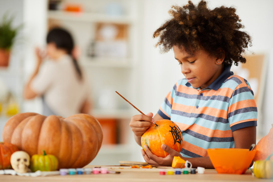 Child painting a pumpkin in his kitchen