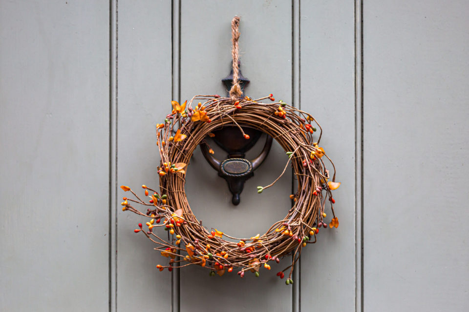 A decorative wreath with berries, hanging on the outside of a door