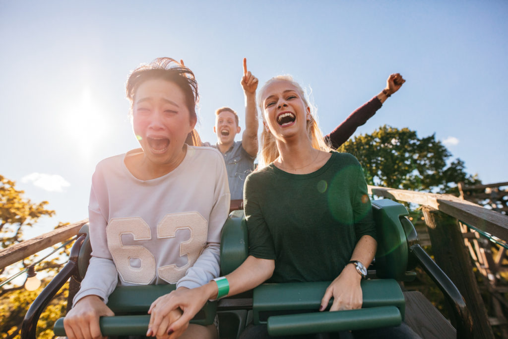 Enthusiastic young friends riding roller coaster ride