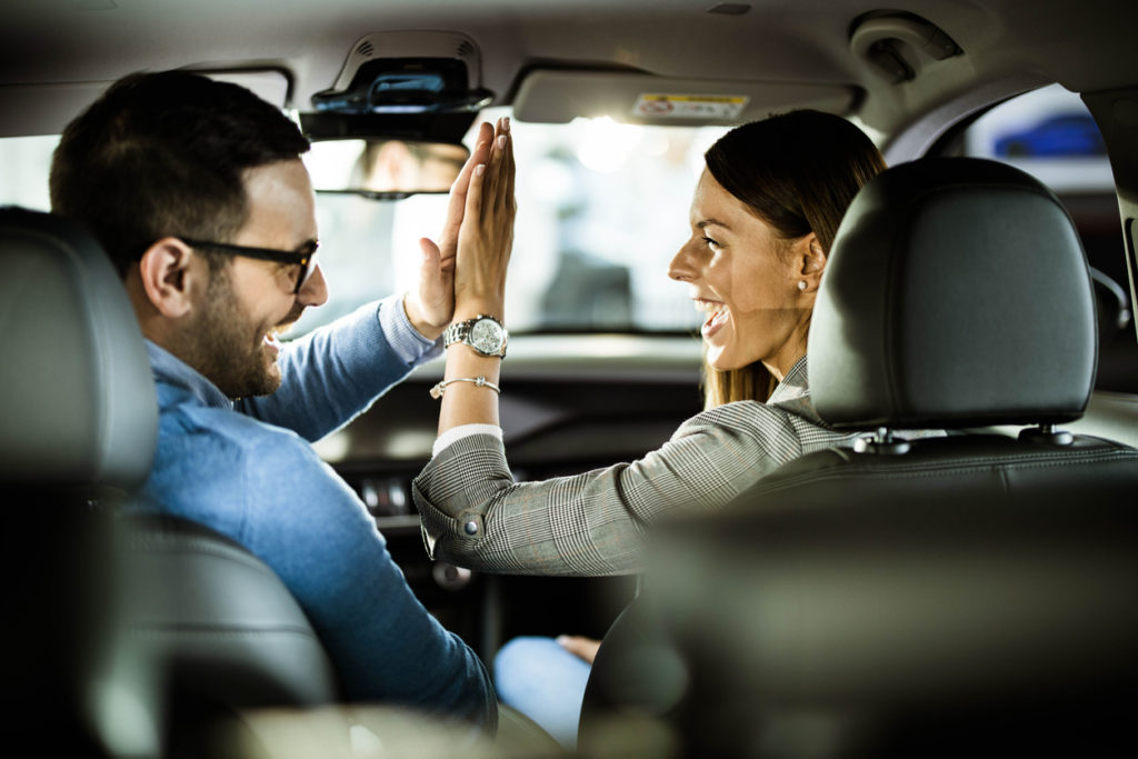 Happy couple high fiving after buying a car